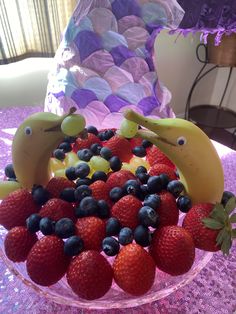 some fruit in the shape of dolphins on a table with purple sequins and strawberries