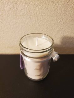 a glass jar with a candle inside sitting on a table