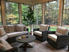 a living room with couches and chairs in front of large windows overlooking the yard