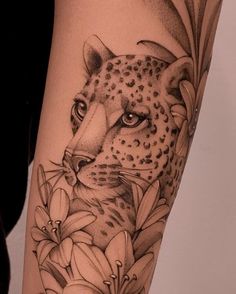 a black and white photo of a leopard with flowers on it's leg,