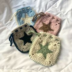 three crocheted coin purses sitting on top of a white bed covered in sheets