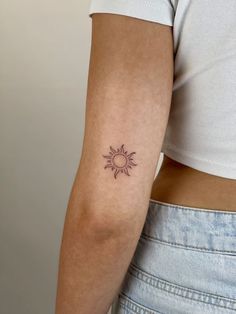 a woman's arm with a small sun tattoo on the back of her left arm