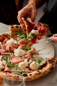 a person taking a slice of pizza from a plate