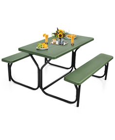 a green picnic table with two benches and plates of food on the table next to it