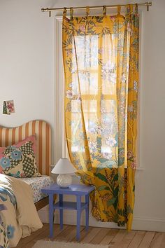 a bed room with a neatly made bed and a yellow drape on the window