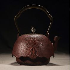 a brown teapot with a handle on it's side and a flower design on the front