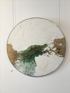 a round mirror hanging on the wall with paint and gold leafy designs in it