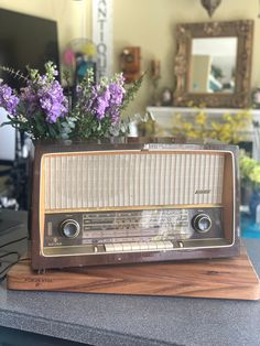 an old fashioned radio sitting on top of a counter next to a vase with flowers