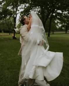 a bride and groom kissing in the park