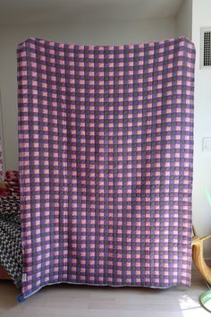 a purple and black checkered blanket sitting on top of a bed