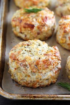 several crab cakes on a baking sheet with fresh rosemary sprigs and seasoning