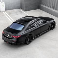 a black sports car parked in a parking lot next to a building with white lines on the floor