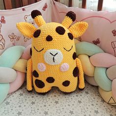 a stuffed giraffe sitting on top of a bed next to pillows