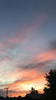 the sun is setting behind power lines and telephone poles