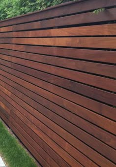 the side of a wooden fence with grass and trees in the background