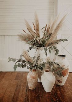 three vases with plants in them on a wooden floor