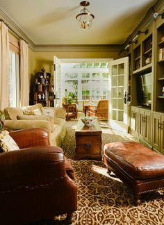 a living room filled with lots of furniture and bookshelves next to a window