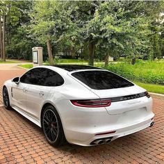 a white porsche panamera parked in front of trees