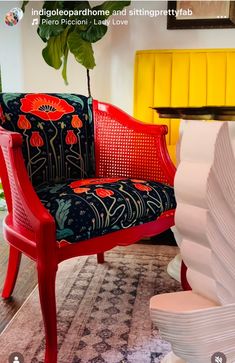 a red chair sitting on top of a rug next to a white vase