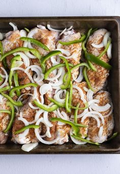 a pan filled with meat covered in onions and green peppers