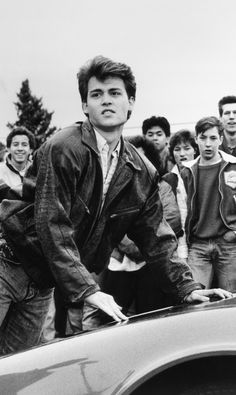 a group of young men standing around a car