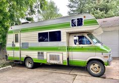 a green and white camper parked in front of a garage