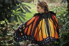 a woman dressed as a butterfly sitting in the woods