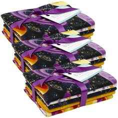 a stack of cloths with purple ribbon tied around them and space themed designs on them