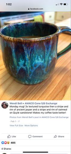 a coffee cup sitting on top of a wooden table next to a cell phone screen