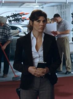 a woman standing in front of a car with other people looking at the cars behind her