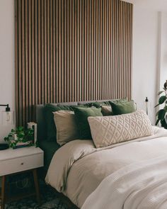 a bed with white sheets and green pillows