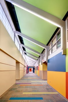 an empty hallway with multicolored walls and wood flooring on both sides is shown