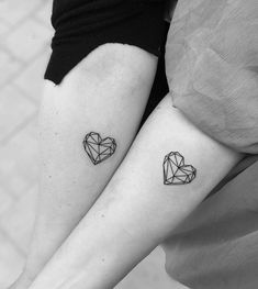 two people with tattoos on their legs, one has a heart and the other has an origami