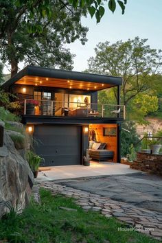 a modern house with an open garage door and lights on the roof, surrounded by trees