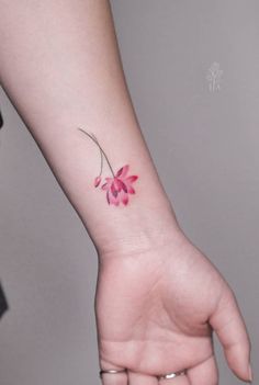 a small pink flower tattoo on the wrist