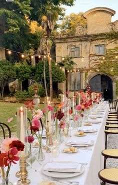 a long table is set up with flowers and candles for an outdoor dinner in the garden