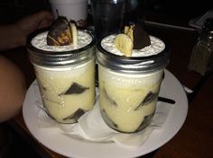 two mason jars filled with desserts sitting on top of a white plate next to each other