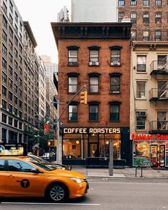 a yellow taxi driving down a street next to tall buildings