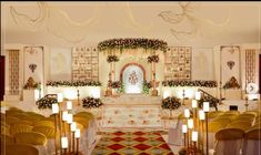 the interior of a wedding ceremony with gold chairs and floral decorations on the wall, candles lit up in front of the altar