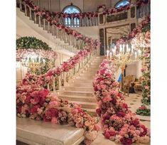 an elaborate staircase decorated with pink flowers and greenery for a wedding ceremony at the grand america hotel