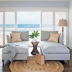 a living room with two couches and a rug in front of the window overlooking the ocean