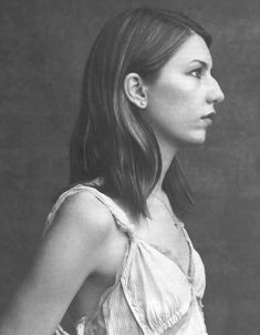 a black and white photo of a woman with shoulder length hair wearing a halter top