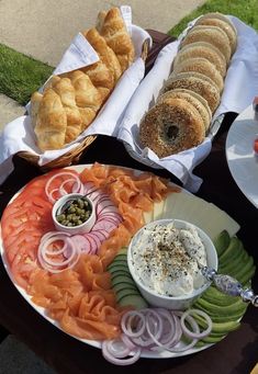 an assortment of food is displayed on a picnic table with breads and dips