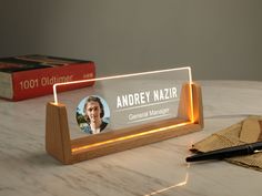 a wooden desk with a light up sign and pen on it next to two books