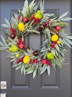 a wreath with fruit and greenery on the front door