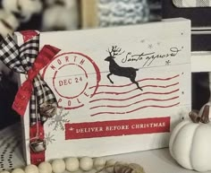 a white wooden sign with a red ribbon around it and some decorations on the table