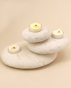 three candles sitting on top of white rocks