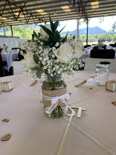 a vase filled with white flowers sitting on top of a table next to other tables