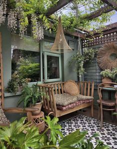 an outdoor patio with wicker furniture, potted plants and greenery hanging from the roof