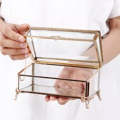 a person holding a glass box with chains on the bottom and inside, in front of a white background